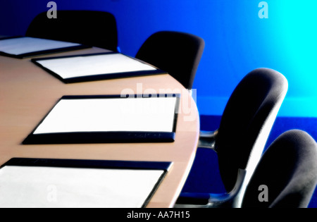 Sedie nere e blotter pad in pelle su una scrivania in legno in una sala riunioni vuota Foto Stock