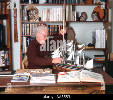 Senior Citizen la costruzione di un modello di nave in casa sua Foto Stock