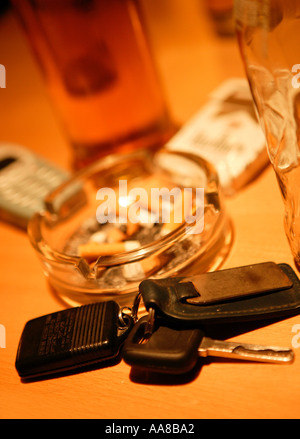 Le chiavi dell'auto sul tavolo di pub con POSACENERE E LA BEVANDA ALCOLICA IN BACKGROUND Foto Stock