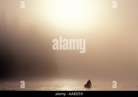 Una canoa scivola attraverso la nebbia e la nebbia di mattina d'estate sul fiume Restigouche nel nord di New Brunswick Canada Foto Stock