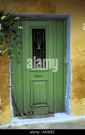 Verde pallido set porta in un dipinto di giallo con il muro di blu pallido rivelano appeso con caprifoglio Foto Stock