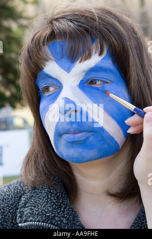 Donna con la faccia dipinta di Scottish bandiera nazionale, bianco su blu si intraversa Foto Stock