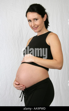 Donna incinta che indossa un top nero e pantaloni Foto Stock