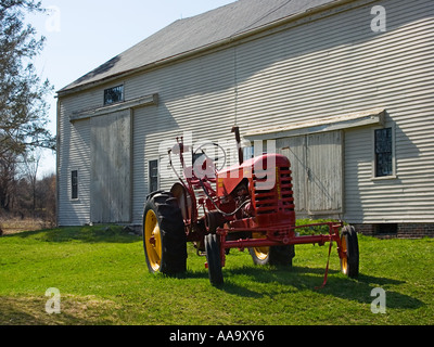 Un vecchio Massey Harris Farm trattore parcheggiato di fronte a un antico New England barn Foto Stock