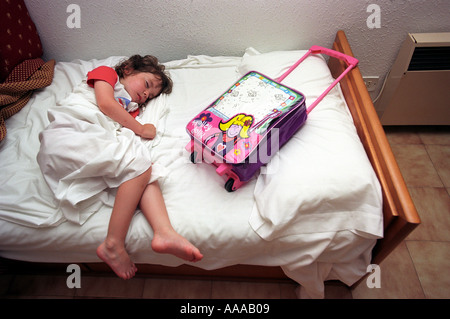 Un bambino addormentato con borsa da viaggio dopo un lungo viaggio Foto Stock