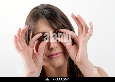 Giovane donna tenendo l'Ammonita gusci che è stata divisa a metà e altamente lucidato guardando al passato o il futuro Foto Stock