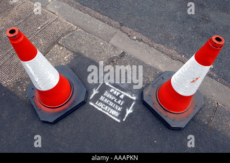 Due coni di traffico di proteggere un cartello Pay & display LA POSIZIONE DELLA MACCHINA Foto Stock