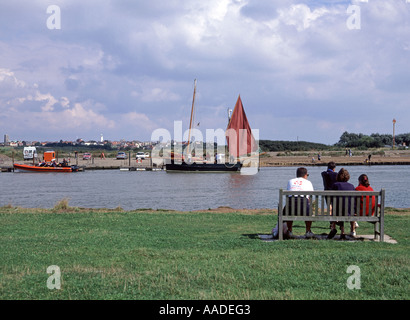 Persone Walberswick rilassante accanto a marea alta con Southwold litorale e del faro al di là Foto Stock