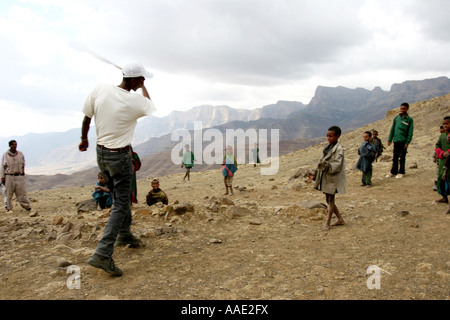 Trek Guide gioca palla con bambini locali durante il trekking in Simien Mountains National Park, Etiopia, Africa Foto Stock