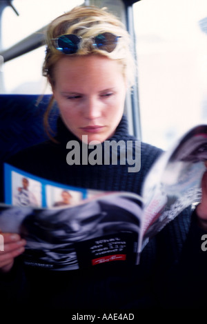 Lettura della ragazza magazine sui mezzi di trasporto pubblico di Londra Foto Stock