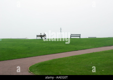 Due pensionati seduti su una panchina che guarda al mare in un mare di nebbia sul fronte mare, a Bexhill-on-Sea, Sussex, Regno Unito. Maggio 2007. Foto Stock