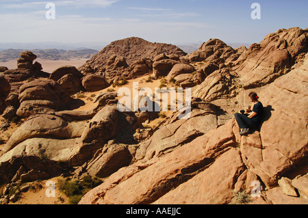 Trekker si ammira un panorama da un solitario vertice di Wadi Rum Area protetta della Giordania Foto Stock