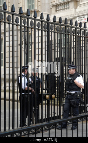 Tre uniformata guardie di polizia, due all'interno e uno esterno cancelli principali a Downing Street, London, England, Regno Unito Foto Stock