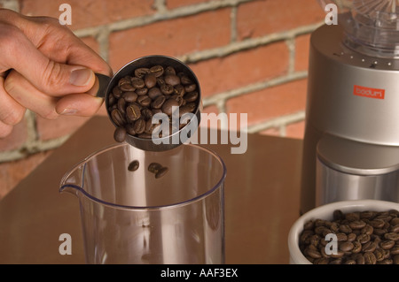 Versare i chicchi di caffè in una caraffa per posizionare su una scala di caffè Foto Stock