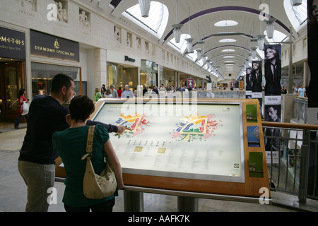 Gli amanti dello shopping utilizzando la tabella di orientamento e la directory del negozio a Bluewater shopping mall, England, Regno Unito Foto Stock