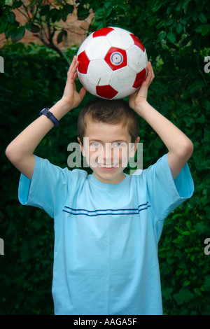 Ragazzo tenendo il calcio sopra la sua testa Foto Stock