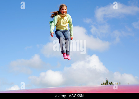 Una giovane ragazza saltando su un grande trampolino di gomma Foto Stock