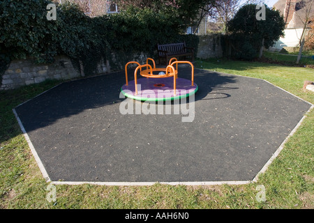 Piccola Merry Go Round sui giochi per bambini circondata da stuoie di sicurezza realizzato da vecchi pneumatici per auto UK Foto Stock