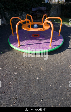 Piccola Merry Go Round sui giochi per bambini circondata da stuoie di sicurezza realizzato da vecchi pneumatici per auto UK Foto Stock