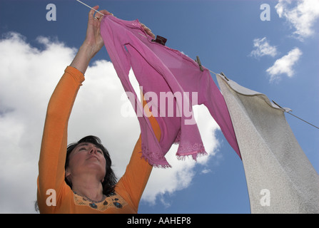 Donne appendere fuori i vestiti sulla linea di lavaggio Foto Stock