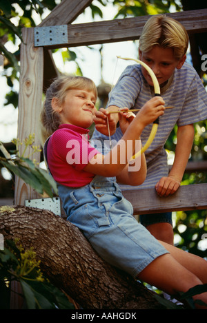 I bambini in treehouse giocando con arco e frecce Foto Stock