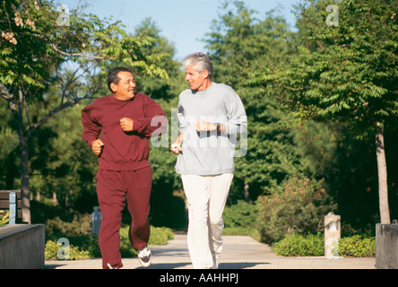 Vecchi uomini anziani fare jogging lungo il sentiero percorso diversità etnico razziale diverse African American caucasian parlando di uomini sorridenti jogging il pensionamento in pensione Foto Stock