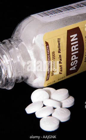 Primo piano della bottiglia di aspirina con alcune compresse versate fuori, simboleggiando la medicina, la salute, e sollievo dal dolore, USA. Foto Stock