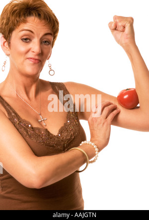 Primo piano della mezza età donna caucasica (35-40) con il pomodoro schiacciato nel muscolo del braccio, resistenza e stile di vita sano Foto Stock