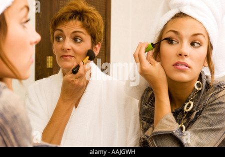 Madre (35-40) e Teen (16-18) Figlia di applicare il trucco per il viso, cosmetici e ottenere pronto ad andare fuori Foto Stock