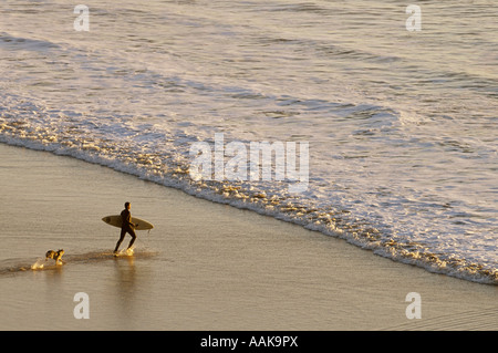 Surfer di uscire a onde con cane in esecuzione dopo di lui indiano Ecoloa Beach State Park northern Oregon Coast Foto Stock