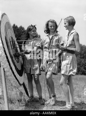 1930s 1940s tre ragazze adolescenti in piedi dal bersaglio tiro con l'arco archi frecce Foto Stock