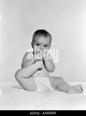 Anni Cinquanta anni sessanta bambino seduto su una coperta portando il piede per la bocca Foto Stock