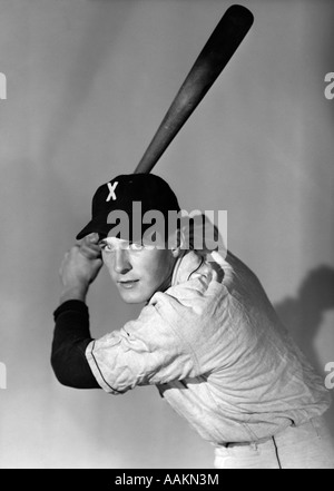 Anni Cinquanta ritratto giocatore di baseball BATTING A BAT guardando la fotocamera Foto Stock