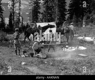 1920s GRUPPO UOMINI DONNE AL CAMPEGGIO ruvida cottura cavalli di fuoco CAMPFIRE DESERTO AVVENTURA TENDA COWBOY CANADA ASSINIBOINE Foto Stock