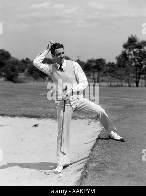 1930s uomo golfista sabbia trappola di graffiare la sua testa Foto Stock