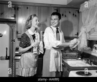 Anni Cinquanta sorridendo felice coppia UOMO E DONNA MARITO E MOGLIE Lavaggio Asciugatura piatti INSIEME IN CUCINA Foto Stock