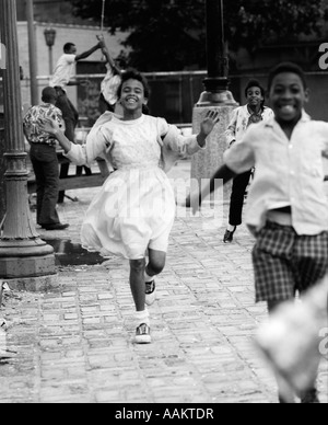 Negli anni settanta del gruppo americano africano di bambini che corre lungo il marciapiede Foto Stock