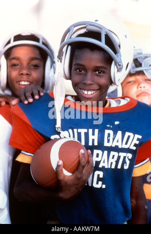 Anni Novanta African American boys tenendo il calcio indossano uniformi e caschi Foto Stock