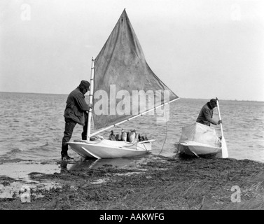 Negli anni Trenta due uomini di piccole imbarcazioni DUCK DECOY preparando andare anatre caccia Foto Stock