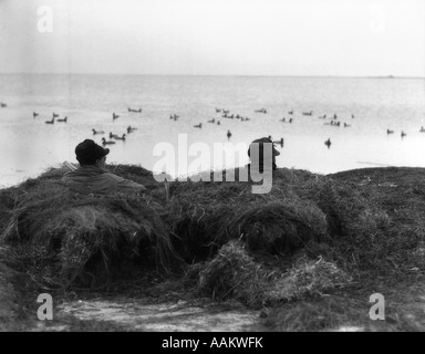 Negli anni Trenta due uomini camuffati in anatra caccia cieco Foto Stock