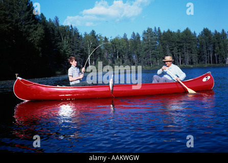 Anni sessanta nonno & BOY RED canoa sul lago pesca sportiva nipote trattura nella cattura di pesce famiglia famiglie generazioni Foto Stock