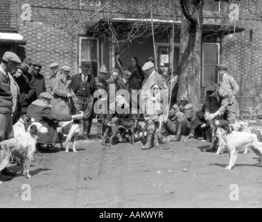 1920s 1930 cani da caccia con istruttori assemblati per prove sul campo di fronte all edificio in mattoni Foto Stock