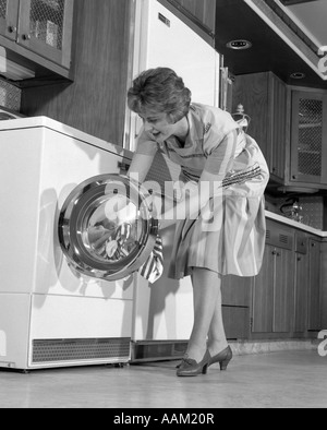 Anni sessanta massaia IN CUCINA mettendo il bucato nel rondella Foto Stock