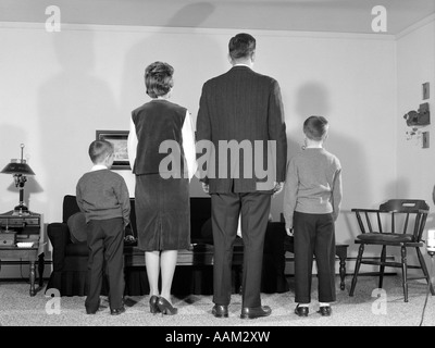 Anni sessanta VISTA POSTERIORE FAMIGLIA DI QUATTRO PERSONE IN PIEDI NEL SOGGIORNO madre padre due ragazzi Foto Stock