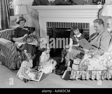 Degli anni Cinquanta la famiglia di cinque madre padre e tre ragazze seduti davanti al soggiorno e caminetto mantello Foto Stock