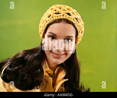 Anni Settanta ritratto sorridente giovane capelli lunghi BRUNETTE donna che indossa giallo cappuccio A CROCHET Foto Stock