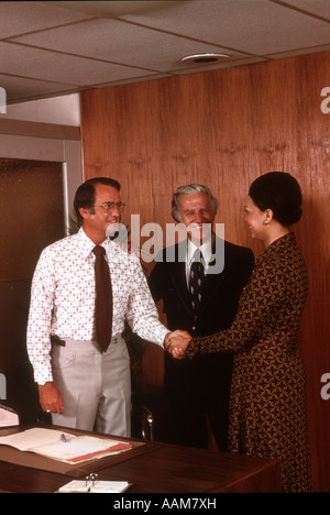 1970 anni settanta 2 uomini uno afro-donna americana business meeting agitando mani accordo saluto Foto Stock
