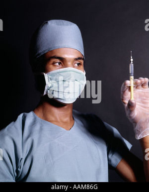 Anni Settanta afro-americano medico infermiere mascherina chirurgica vestaglia guanti tenendo la siringa ipodermica un ago da iniezione SHOT Foto Stock