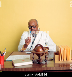 AFRICAN AMERICAN medico seduto alla scrivania Foto Stock