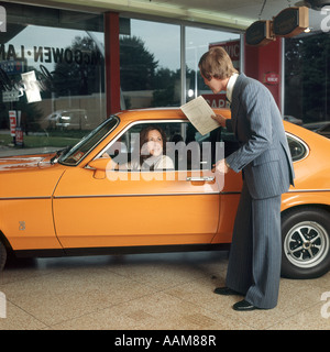 Donna alla guida di auto di colore arancione come ottenere assistenza DA UOMO IN BUSINESS SUIT aiutare a parlare Foto Stock
